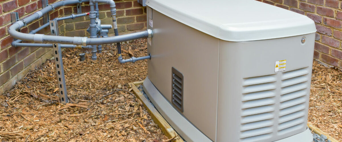 Beige residential standby generator unit mounted on wooden base against brick wall with gray PVC piping connections.