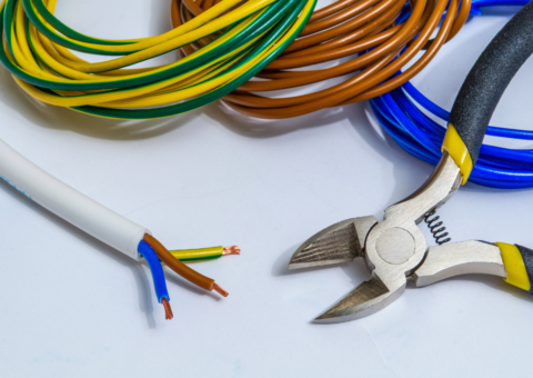 Electrical Wire Stripping and Repair Tools Wire strippers with yellow handles cutting colored electrical wires next to coiled cables in various colors including yellow-green, brown, and blue.